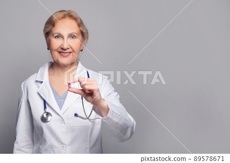 Portrait of senior doctor with medical pill remedy on grey background 89578671
