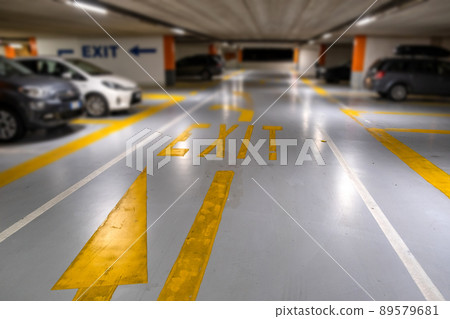 Yellow markings with blurred modern cars parked inside closed underground parking lot. 89579681