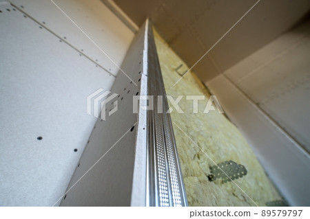 Wall of a room under renovation with mineral rock wool insulation and metal frame prepared for drywall plates. 89579797