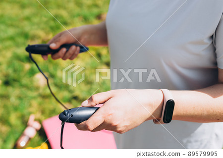 Close up of woman jumping, girl using skipping rope in park, summer sunny day Close up of woman jumping, girl using skipping rope in park, summer sunny day 89579995