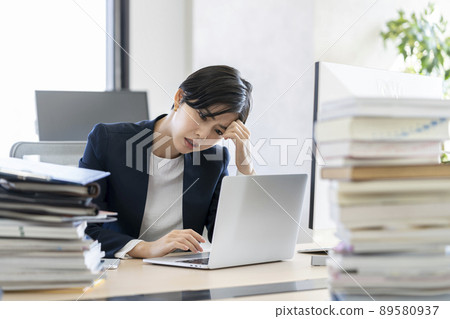 Desk work A business woman holding her head while looking at the screen of a laptop computer Desk work A business woman holding her head while looking at the screen of a laptop computer 89580937