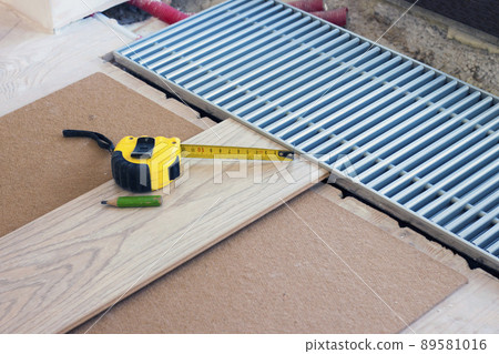 Measuring tape and a pencil on laminate floor plank 89581016