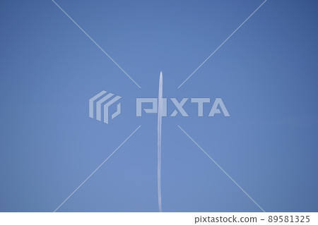 Distant passenger jet plane flying on high altitude on clear blue sky leaving white smoke trace of contrail behind. Air transportation concept. 89581325