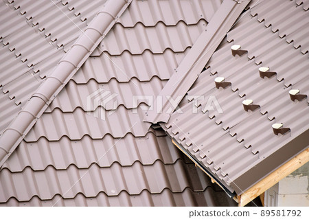 Closeup snow guard for safety in winter on house roof top covered with steel shingles. Tiled covering of building Closeup snow guard for safety in winter on house roof top covered with steel shingles. Tiled covering of building 89581792