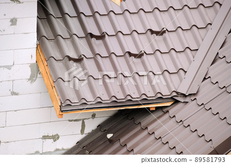 Closeup snow guard for safety in winter on house roof top covered with steel shingles. Tiled covering of building 89581793