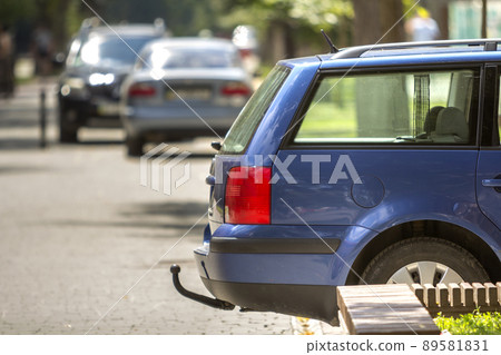 Blue car parked on sunny street, red stop lights, hook for dragging trailer, tow hitch or towbar. 89581831