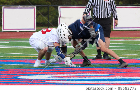 Fighthing for the ball during a face off in a lacross game Fighthing for the ball during a face off in a lacross game 89582772