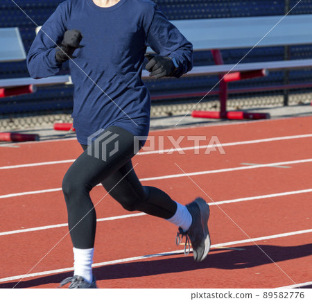 Runner running fast on a track wearing gloves Runner running fast on a track wearing gloves 89582776
