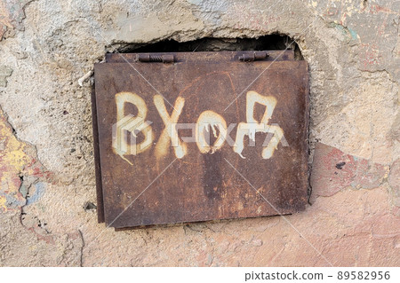 A metal sheet with the inscription Entrance closes the basement of a residential building 89582956