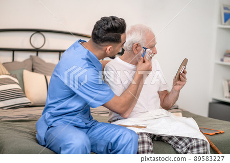 Caretaker shaving off sideburns of an old gentleman Caretaker shaving off sideburns of an old gentleman 89583227
