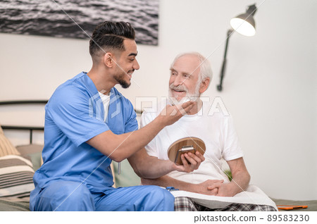 Cheerful caregiver preparing an aged male person for a shave 89583230