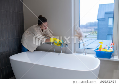 A housewife disinfecting the bathroom at home 89583251