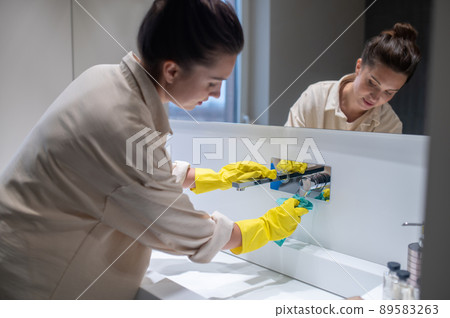 A young housewife cleaning in the bathroom 89583263