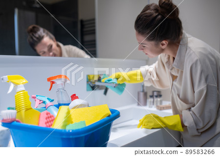 A young housewife cleaning in the bathroom A young housewife cleaning in the bathroom 89583266