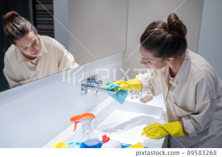 A young housewife cleaning in the bathroom A young housewife cleaning in the bathroom 89583268