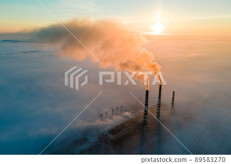 Aerial view of coal power plant high pipes with black smoke moving up polluting atmosphere at sunrise. Aerial view of coal power plant high pipes with black smoke moving up polluting atmosphere at sunrise. 89583270