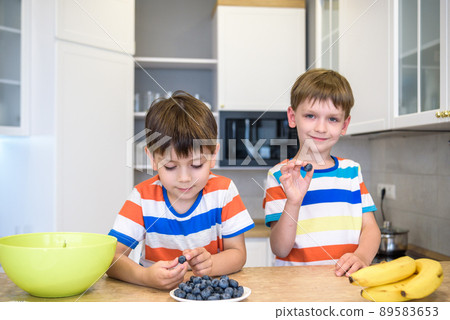 Happy child decorating meringue with blueberries . Child helping in kitchen Happy child decorating meringue with blueberries . Child helping in kitchen 89583653