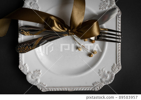 Romantic tabble setting with ribbon, plates, cutlery on black background. Empty plate. Mockup design layout for your text. Love romantic concept. Copy space. Top view. Flat lay. Romantic tabble setting with ribbon, plates, cutlery on black background. Empty plate. Mockup design layout for your text. Love romantic concept. Copy space. Top view. Flat lay. 89583957