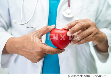 Doctor holding a red heart in hospital ward, healthy strong medical concept. Doctor holding a red heart in hospital ward, healthy strong medical concept. 89583968