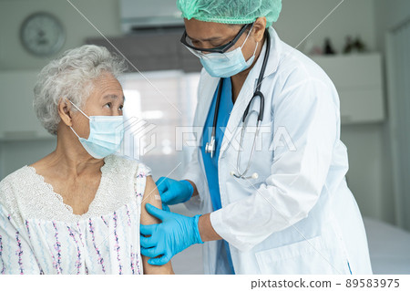 Elderly Asian senior woman wearing face mask getting covid-19 or coronavirus vaccine by doctor make injection. 89583975