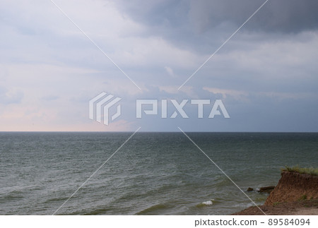 A cloudy grey sky shrouds the white foamy tipped teal waters of this beach. A cloudy grey sky shrouds the white foamy tipped teal waters of this beach. 89584094