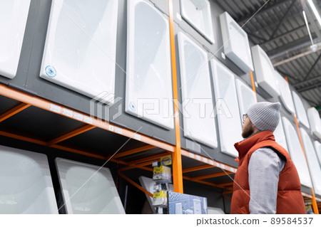 a man in a plumbing store chooses a new acrylic bathtub a man in a plumbing store chooses a new acrylic bathtub 89584537