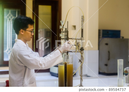 Asian man scientist make sediment experiment with old equipment and measuring cylinder in the laboratory Asian man scientist make sediment experiment with old equipment and measuring cylinder in the laboratory 89584737
