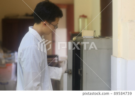 Asian man scientist checking drying and heating oven in the laboratory Asian man scientist checking drying and heating oven in the laboratory 89584739