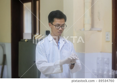 Asian man scientist operating a rotary evaporator to make an experiment in the laboratory Asian man scientist operating a rotary evaporator to make an experiment in the laboratory 89584760