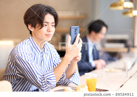 A young man staring at the screen of a smartphone at a cafe 89584911