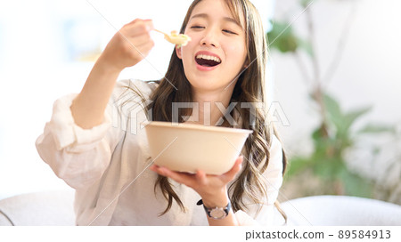 Young woman eating vegetables with a salad bowl in her hand 89584913
