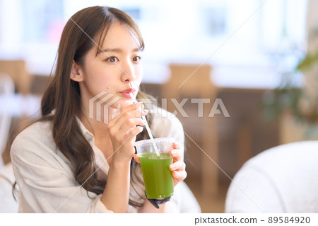 Young woman drinking vegetable juice with a straw 89584920