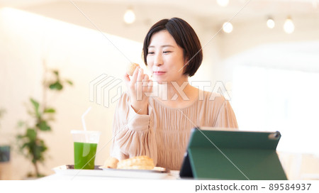 一個微笑的年輕女子在吃飯時使用電腦 89584937