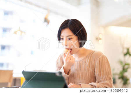 年輕女子在吃飯時使用電腦 89584942