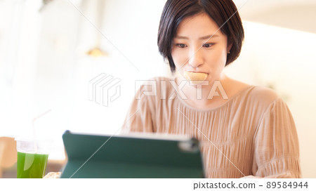 A young woman using a PC while holding bread 89584944