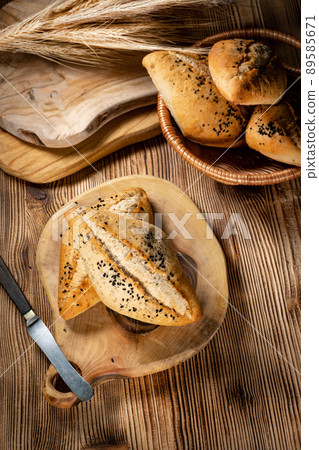 Fresh bread rolls on a rustic wooden table. 89585671
