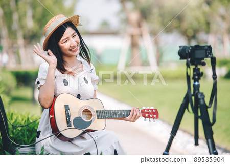 Asian woman influencer playing guitar in the park for make a content, lifestyle and recreation concept. Asian woman influencer playing guitar in the park for make a content, lifestyle and recreation concept. 89585904