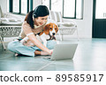Young Freelancer Asian Woman Working Online via Social Media with Beagle Dog Using Laptop at Home Living Room 89585917