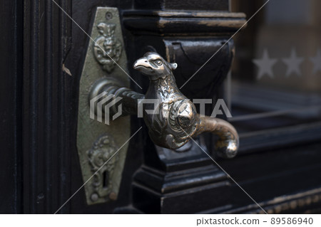 Old door handle. Wooden vintage entrance door with antique door handles in the shape of bird. Selective focus Old door handle. Wooden vintage entrance door with antique door handles in the shape of bird. Selective focus 89586940