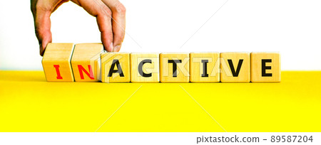 Active or inactive symbol. Businessman turns wooden cubes and changes the word Inactive to Active. Beautiful yellow table white background, copy space. Business and active or inactive concept. Active or inactive symbol. Businessman turns wooden cubes and changes the word Inactive to Active. Beautiful yellow table white background, copy space. Business and active or inactive concept. 89587204