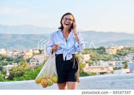 Outdoor portrait of beautiful mature woman with smartphone, summer nature sky 89587397