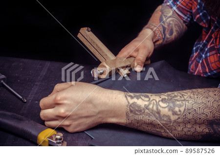 Leather workman at work on his new leather product in the leather studio Leather workman at work on his new leather product in the leather studio 89587526
