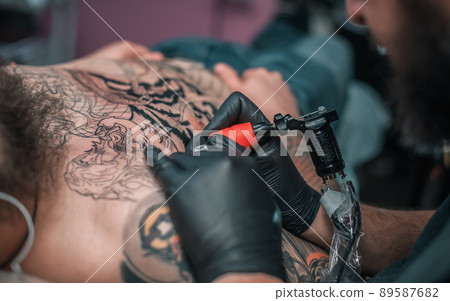 Professional tattooist makes a tattoo on the skin in a workshop studio 89587682