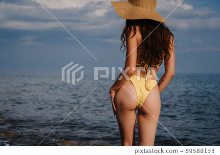 sexy ass of a slender girl in a swimsuit in a straw hat on the beach at the sea sexy ass of a slender girl in a swimsuit in a straw hat on the beach at the sea 89588133