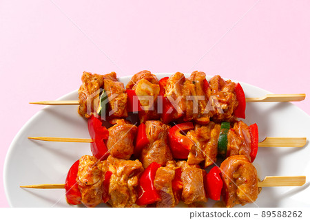 raw marinated meat on wooden skewers, pork, chicken, beef in white plate on pink background. raw marinated meat on wooden skewers, pork, chicken, beef in white plate on pink background. 89588262