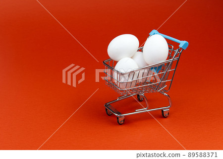 chicken white eggs in a shopping cart. isolated on orange 89588371