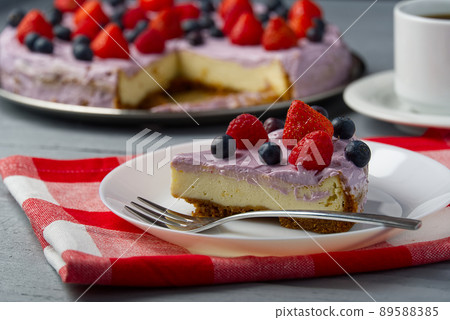 Piece of home made Cheesecake with berries on plate and mug of Americano coffee. Cheesecake with Strawberry, blueberry and raspberry on grey wooden background. Piece of home made Cheesecake with berries on plate and mug of Americano coffee. Cheesecake with Strawberry, blueberry and raspberry on grey wooden background. 89588385