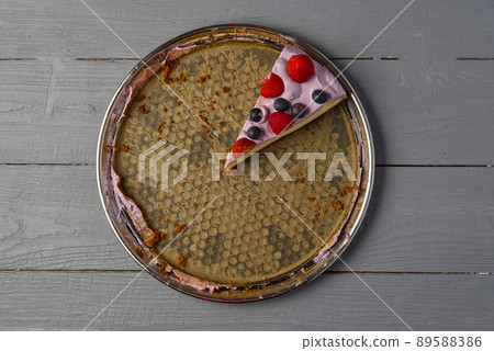 Last slice of home made Cheesecake with berries on plate on grey wooden background. 89588386