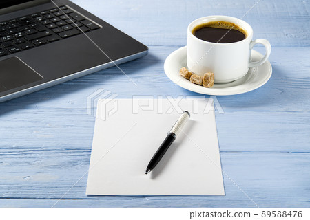 Laptop with cup of coffee on light blue old wooden table. Notebook with cup of fresh coffee in home office. Working from home concept Laptop with cup of coffee on light blue old wooden table. Notebook with cup of fresh coffee in home office. Working from home concept 89588476