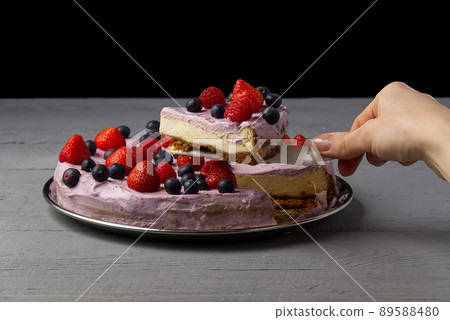 Woman divided cheesecake and take one slice to offer it. Home made Cheesecake with Strawberry, blueberry and raspberry on grey wooden background. Woman divided cheesecake and take one slice to offer it. Home made Cheesecake with Strawberry, blueberry and raspberry on grey wooden background. 89588480